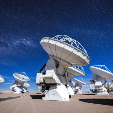 ALMA's DV-59 antenna in the foreground with multiple other antennas observing the sky in a night dominated by the Moon.